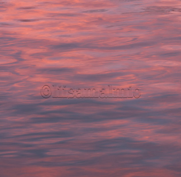 auringonlaskun punaiset sävyt heijastuvat joen pinnalla Porvoossa